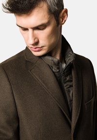 Brązowa marynarka z mieszanki wełny z ocieplaną, zapinaną na zamek kurtką wewnętrzną. Posiada klapę o fasonie notched oraz kieszeń na piersi. Gładka faktura, dopasowany krój.