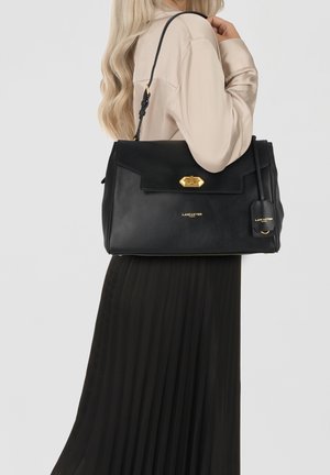 Borsa a tracolla in pelle nera con un design strutturato, hardware dorato, patta frontale e etichetta staccabile. Dotata di una singola tracolla.