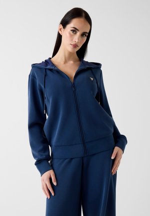Felpa con cappuccio blu navy con zip, realizzata in tessuto liscio, con cappuccio con coulisse, piccolo logo sul petto e polsini e orlo a costine.