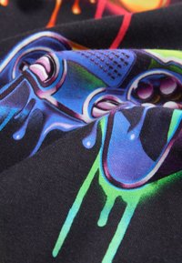 Imprimare grafică colorată pe țesătură neagră, cu motive de jocuri video, cu accente vibrante în albastru, verde și mov, prezentând o suprafață netedă și texturată.