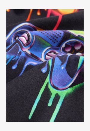 Barevný grafický potisk na černé látce s motivy her, doplněný živými modrými, zelenými a fialovými akcenty, zobrazující hladký, texturovaný povrch.