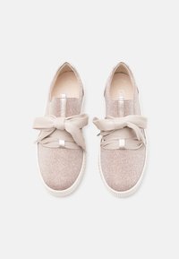 Glanzende lichtroze sneakers met een gestructureerd oppervlak, elastische veters gestrikt in een strik, en een witte rubberen zool. Vlak ontwerp, instapmodel.