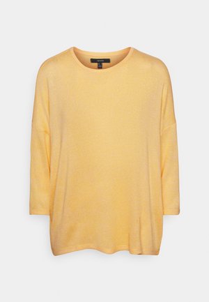 Gul löst sittande stickad tröja med rund hals och trekvartslånga ärmar på en enfärgad bakgrund.