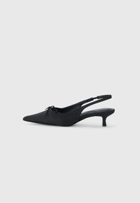 Tacchi slingback neri con punta affusolata, tessuto testurizzato, un piccolo dettaglio a forma di fiocco nella parte anteriore e un tacco kitten modesto.