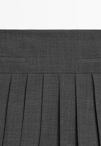 Jupe plissée gris foncé avec une large ceinture et deux poches fendues horizontales près du bord supérieur.