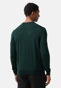 Ciemnozielony sweter wykonany na drutach z długimi rękawami, okrągłym dekoltem i ściągaczem na dole. Teksturowany materiał z minimalnymi detalami, dopasowany krój.