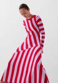 Rood en wit gestreepte jurk met lange mouwen, een aansluitend bovenstuk en een uitlopende rok, met een ribbelstructuur door de hele jurk.