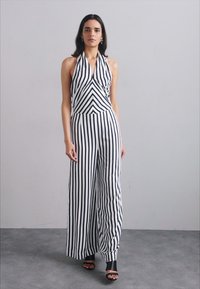 Black and white striped jumpsuit with halter neck design, wide-leg cut, and ruched detailing at the bodice. Smooth fabric texture.