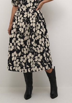 Sort midi-nederdel med hvidt blomsterprint, tekstureret stof, indsnævret talje og plisseringer, kombineret med sorte cowboystøvler.