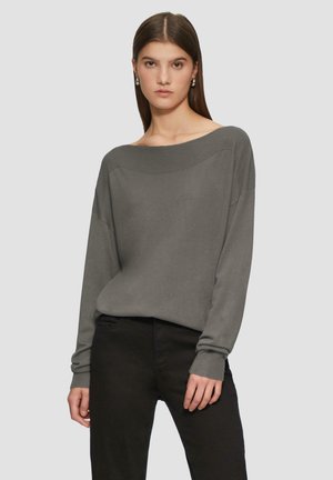 Grijze off-shoulder trui met lange mouwen, geribbelde halslijn en manchetten, gecombineerd met zwarte broek met een soepele textuur.