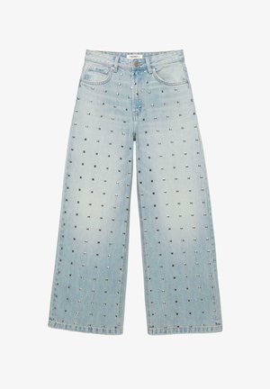 Hellblaue Jeans mit weitem Bein und hoher Taille, mit silbernen quadratischen Nieten gleichmäßig auf dem Vorderstoff verteilt.