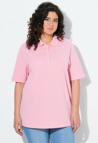 Jasnoróżowa koszulka polo z krótkimi rękawami, klasycznym kołnierzykiem i zapięciem na guziki z przodu. Wykonana z miękkiego, teksturowanego materiału. Luźny krój.