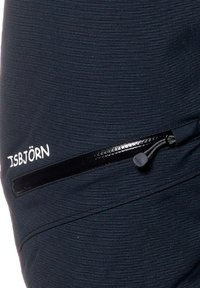 Svart tyg med horisontella ränder, med en zippered ficka som har en glansig finish och en dragrem. Inkluderar "ISBJÖRN"-logotyp.