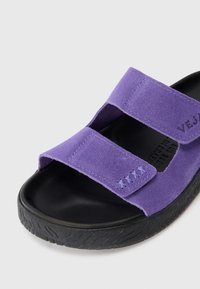 Lila mockaskinnsandaler med två justerbara remmar och en svart texturerad gummisula.