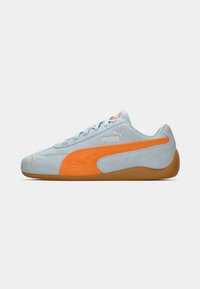 Sapatilhas de camurça azul claro com uma faixa lateral laranja e sola de borracha de goma. Apresenta o logotipo prateado da Puma e detalhes texturizados na parte superior.