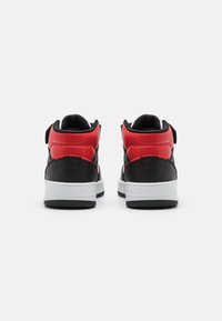 Svart og rød midt-top sneakers med en glatt skinnoverdel, hvit mellomsole og teksturert svart gummiyttersåle. Har polstret krage og stropp.
