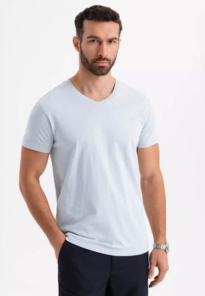 Helles blaues Baumwoll-V-Ausschnitt-T-Shirt, kurze Ärmel, figurbetontes Design, glatte Textur, mit leichtem Stretch, kombiniert mit dunklen Hosen.