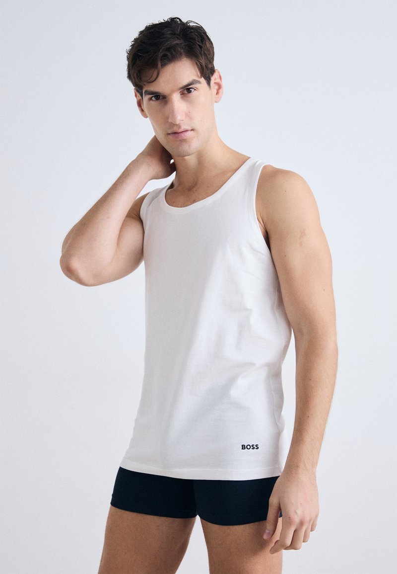 Balta kokvilnas bez piedurknēm, ar apaļu izgriezumu, apvienota ar tumši ziliem šortiem. Bez piedurknēm ir neliels melns "BOSS" logo apakšā.