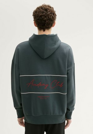 Donkergroen hoodie met een voorste kangoeroezak, witte horizontale strepen en de tekst "Academy Club" in het rood op de achterkant. Zacht stofmateriaal.