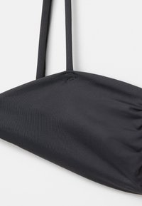 Crni bikini gornji dio od glatkog, rastezljivog materijala. Ima tanke naramenice i detalj nabiranja na čaši.