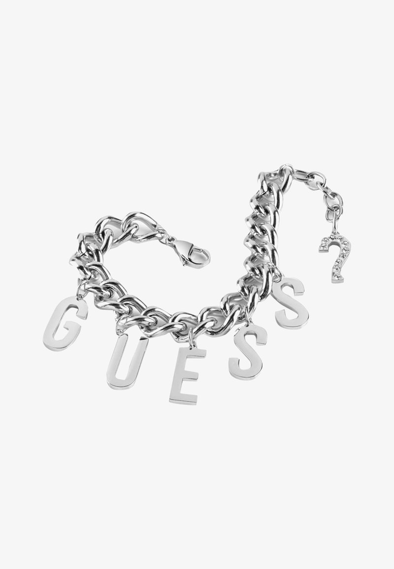 Bracelet chaîne en argent avec de grandes breloques lettres formant "GUESS" et une petite breloque en forme de point d’interrogation ornée de strass près du fermoir.