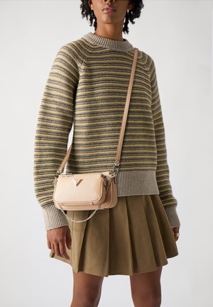 Beige Umhängetasche mit strukturierter Oberfläche und silberner Kette, kombiniert mit einem gestreiften Pullover und einem braunen Faltenrock.