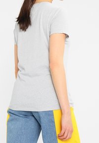 Gray cotton t-shirt with short sleeves and a crew neckline, worn with blue and yellow color-blocked pants. Simple, fitted design.