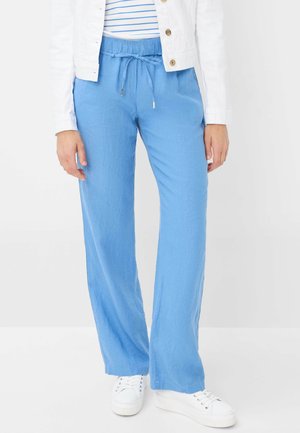 Hellblaue, locker sitzende Hose mit einem elastischen Bund und Kordelzugdetails, kombiniert mit weißen Sneakers. Glatter, atmungsaktiver Stoff.