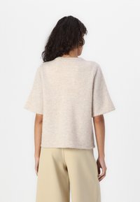 Maglione a maglia beige chiaro con maniche corte, colletto rotondo e texture morbida. Presenta una vestibilità comoda e un orlo dritto. Senza decorazioni.