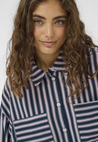 Srajca s sponkami iz bombaža z navpičnimi mornarsko modrimi, roza in belimi črtami, z razprtim ovratnikom in dvema prsnima žepoma.