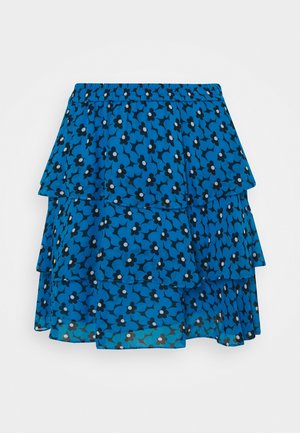 Jupe bleue à volants avec motif floral noir et blanc et ceinture élastique sur fond uni.