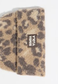 Bufanda de estampado de leopardo en suave lana beige con acentos en marrón oscuro. Presenta una etiqueta cuadrada etiquetada "BIMBA Y LOOLA" cosida en el borde.