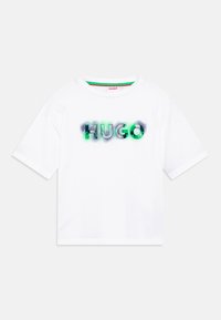 Bílý bavlněný tričko s potiskem 'HUGO' v zelené a černé barvě na přední straně. Krátké rukávy a kulatý výstřih.
