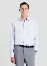 Camicia a maniche lunghe azzurro chiaro con bottone frontale e colletto classico, abbinata a pantaloni grigi su misura e una cintura nera.