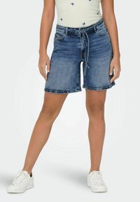 Shorts in denim con vita media, dotati di cintura a nodo, cinque tasche e orlo sfilacciato. Tagliati sopra il ginocchio in un lavaggio blu sbiadito.