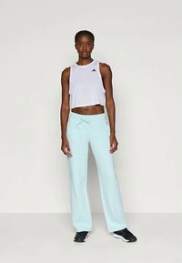 Λευκό κοντό μπλουζάκι με μαύρο λογότυπο, συνδυασμένο με ανοιχτό μπλε παντελόνι φάρδου. Το ρούχο διαθέτει μαλακό ύφασμα και ελαστική μέση.