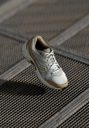 Zapatilla en gris claro y beige, con materiales de malla y ante, puntera redondeada, diseño con cordones y una suela de goma texturizada.