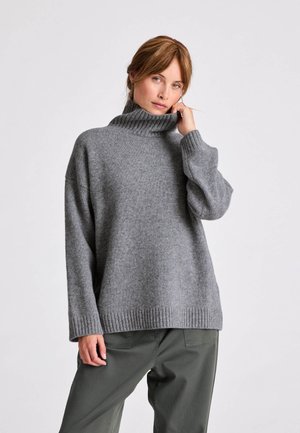 Maglione grigio lavorato a maglia con collo alto a costine, spalle scese e polsini a costine. Vestibilità ampia con una texture morbida. Indossato con pantaloni verde oliva.