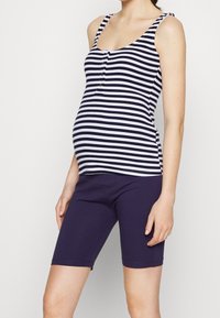 Těhotenský top na ramínka s n�ámořnicky modrými a bílými pruhy, s knoflíkovým detailem, doplněný námořnicky modrými šortkami. Materiál je měkký a strečový.