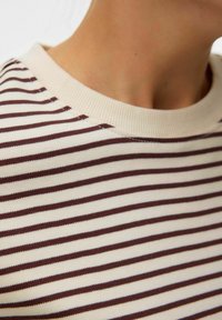 Krämfärgad och brun randig tröja med ribbad rund halsringning och mjukt, strukturerat tyg. Ränderna är jämnt fördelade och halsringningen är slät.