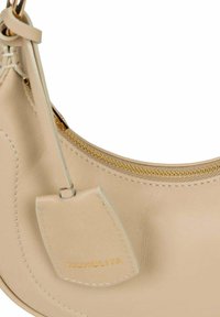 Borsa a mano beige in pelle con design curvo, zip dorata e un piccolo cartellino con la scritta "NOHOLITA". Texture liscia e stile minimalista.