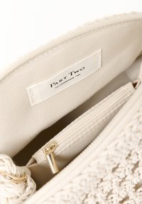 Interno di una borsa beige con texture, dotato di una tasca con zip dorata e un'etichetta in tessuto che recita "Part Two, EST. COPENHAGEN 1984."