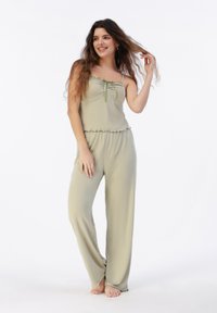 Conjunto de dos piezas verde claro con un escote con volantes y tirantes ajustables en la parte superior, combinado con pantalones sueltos y fluidos.