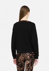 Felpa nera con una vestibilità comoda, caratterizzata da un colletto con stampa leopardata e pantaloni abbinati in stampa leopardata, realizzati in tessuto morbido.