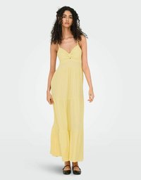 Robe maxi jaune avec fines bretelles, détail de buste froncé et jupe superposée et fluide. Texture lisse en tissu léger.