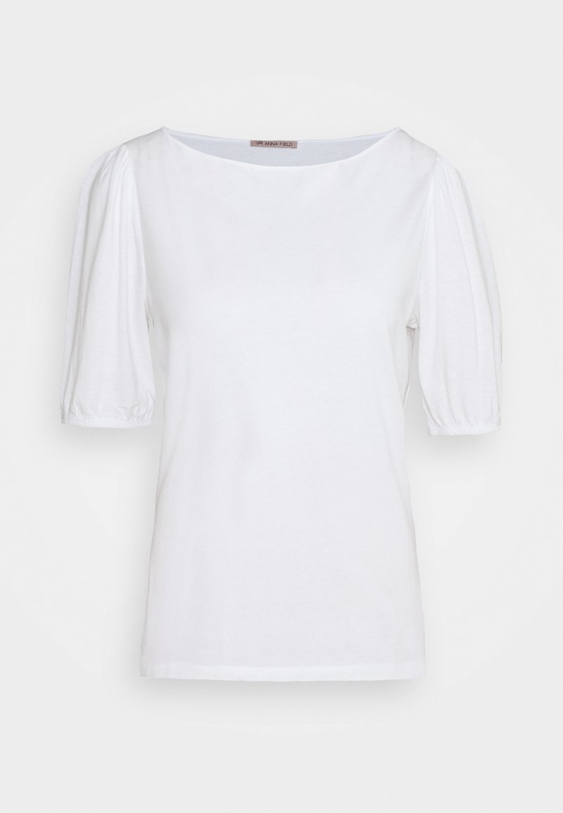 Blouse blanche à manches courtes bouffantes et col rond, présentée sur un fond blanc uni.