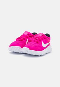 Scarpe sportive rosa brillante con texture a coste, logo swoosh bianco, suola bianca ammortizzata e lacci rosa abbinati.