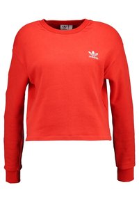 Červená zkrácená mikina vyrobená z měkkého materiálu, s dlouhými rukávy a kulatým výstřihem. Na hrudníku se nachází malé bílé logo Adidas.