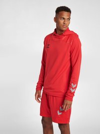Rode sportieve hoodie met een gestructureerde capuchon en logo, gecombineerd met rode shorts met grijze chevronaccenten. Het materiaal lijkt lichtgewicht en ademend te zijn.