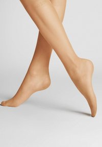 Transparente hautfarbene Strumpfhosen mit einem durchsichtigen Finish, ausgestattet mit einer glatten Textur und einem dezenten Logo-Detail nahe dem oberen Bündchen. Elegantes und figurbetontes Design.